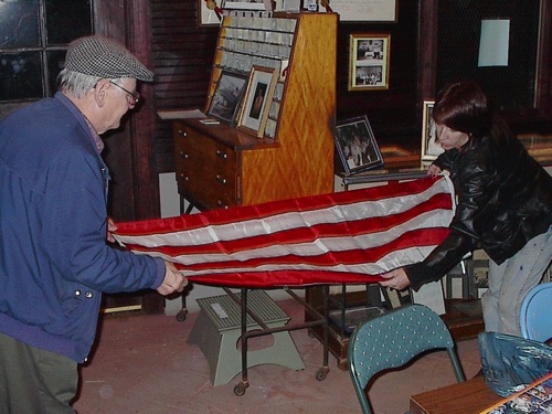 Larry and Mary fold flag in Men’s Waiting Room at the 1915 Erie Station. 12/5/2001 V0010087